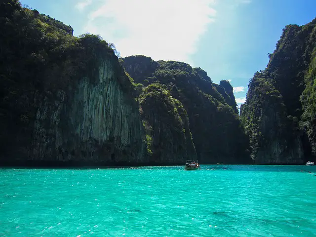 Bateau naviguant sur les eaux turquoise du lagon de Pileh à Koh Phi Phi, une excursion populaire depuis Phuket ou Krabi pour découvrir des paysages de falaises karstiques.