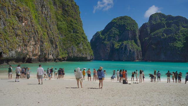 Plage de Maya Bay en Thaïlande bondée de touristes sur le sable blanc devant une eau turquoise, illustrant le problème du surtourisme.