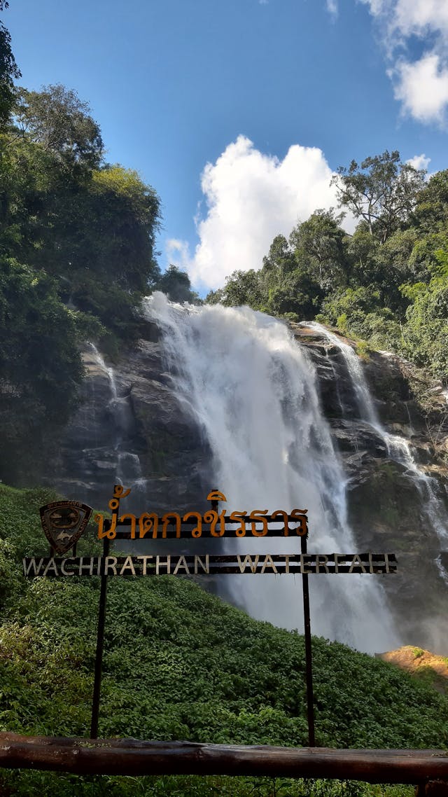 Grande cascade Wachirathan à Doi Inthanon chutant au milieu de la forêt tropicale, avec le panneau Wachirathan Waterfall au premier plan