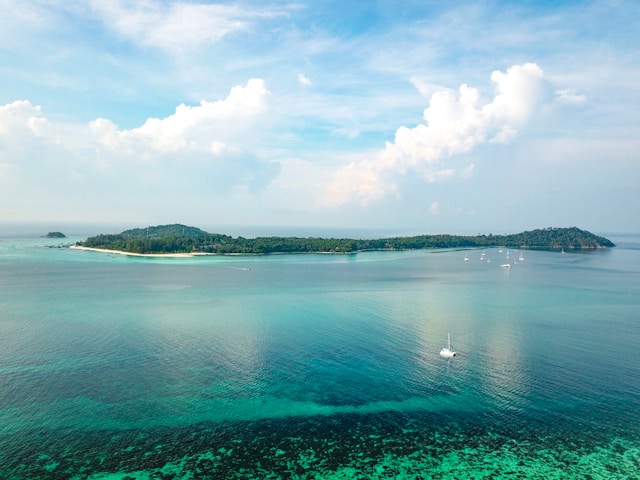 Vue aérienne de Koh Adang avec eau turquoise, plage déserte et quelques voiliers au mouillage face à Koh Lipe