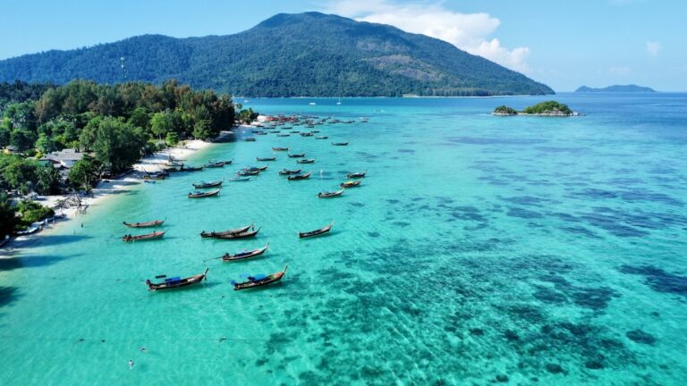 Vue aérienne de Koh Lipe avec eau turquoise, plage de sable blanc et dizaines de long-tail boats alignés