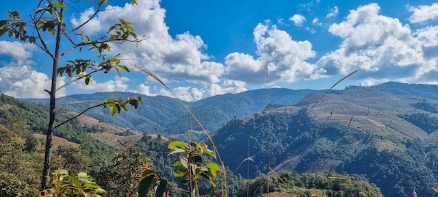 Panorama de collines verdoyantes et de montagnes autour du Doi Inthanon sous un ciel bleu parsemé de nuages