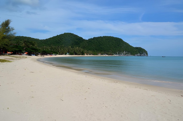 Plage de sable clair de Thong Ching près de Khanom, avec mer calme et collines couvertes de végétation en arrière-plan