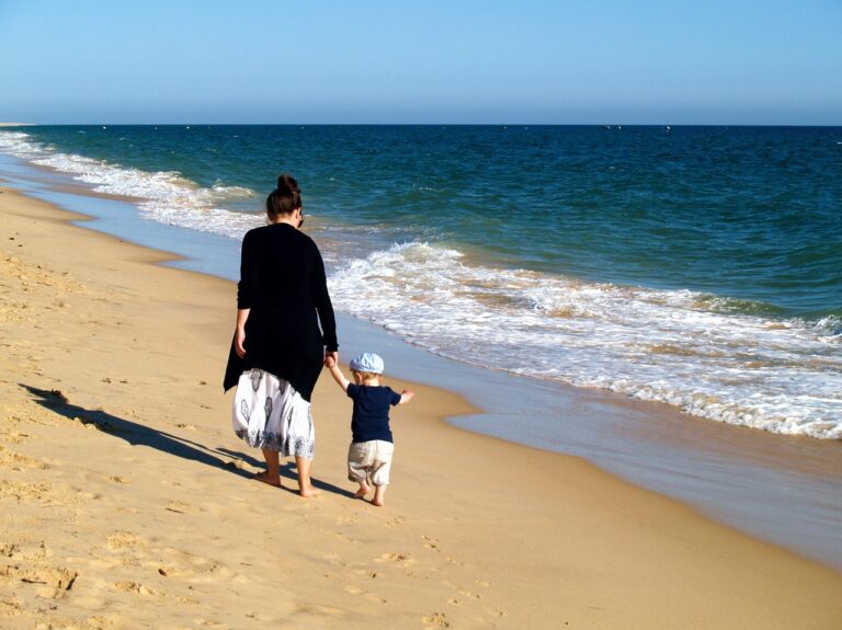 Maman et son bébé marchant main dans la main sur une plage lors d'un voyage en Thaïlande