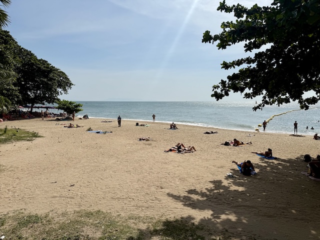 Plage de Dongtan à Jomtien : touristes se reposant à l'ombre naturelle des arbres sur le sable