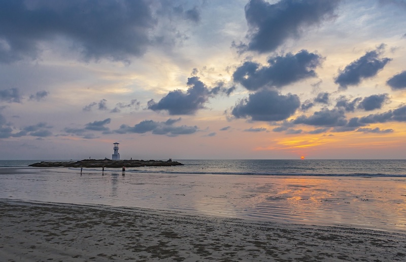 Coucher de soleil sur la plage de Nang Thong à Khao Lak avec le phare emblématique sur les rochers et reflets dorés sur le sable