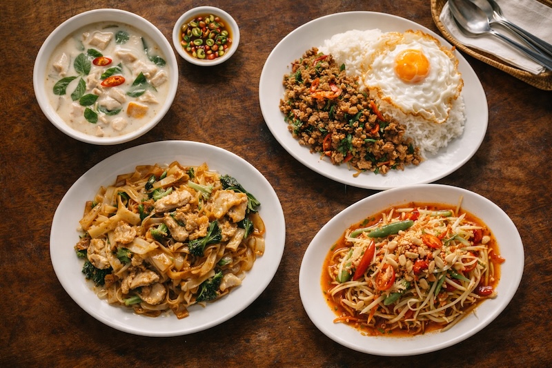 Assortiment de plats thaïlandais avec soupe douce, nouilles sautées, pad kra pao et som tam plus épicé