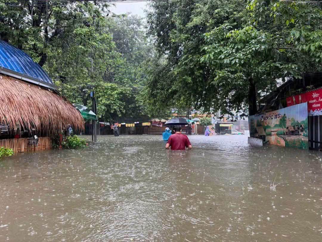 Habitants traversant une rue inondée à Bangkok sous une forte pluie
