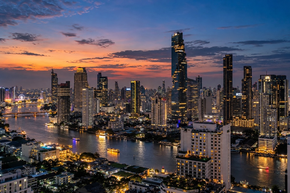 Vue panoramique de Bangkok à la tombée de la nuit, avec les gratte-ciel illuminés et le fleuve Chao Phraya.